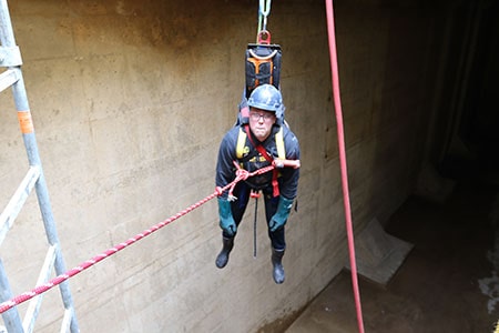 man dangling above confined space